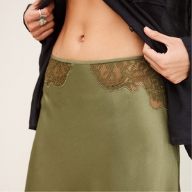 Model wearing Bash Womens French Dress in green satin with lace trim detail at hem, styled with black jacket.