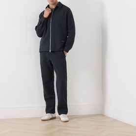 Model wearing Samsoe & Samsoe Dark Grey Mel casual jacket with zip front, styled with matching dark trousers and white trainers.