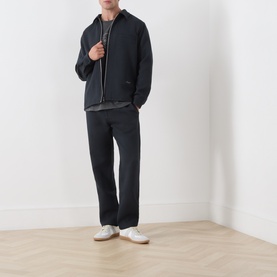 Model wearing Samsoe & Samsoe Dark Grey Mel casual jacket, styled with matching dark trousers, grey top and white trainers.