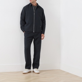 Model wearing Samsoe & Samsoe Jabari Casual Trousers in Dark Grey Mel, straight-leg fit, styled with matching dark zip-up jacket and white trainers.