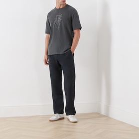 Model wearing Samsoe & Samsoe Black Lines crew neck T-shirt with black straight-leg trousers and white trainers.