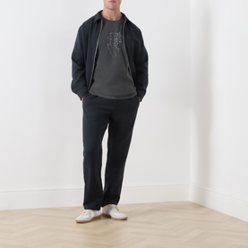Model wearing Samsoe & Samsoe Black Lines crew neck T-shirt, styled with dark zip-up hoodie, black trousers and white trainers.
