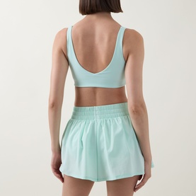 Model wearing Tala SkinLuxe Contrast Piping Sports Bra in Soft Mint, showing V-shaped scoop back detail, styled with matching mint shorts.