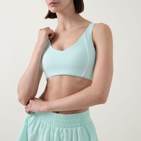 Model wearing Tala SkinLuxe Contrast Piping Sports Bra in Soft Mint, V-neckline with white contrast piping detail, paired with matching mint shorts.
