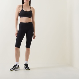 Model wearing Tala Shadow Black cropped leggings with matching sports bra, white ankle socks and grey chunky trainers