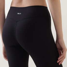 Model wearing Tala leggings in Shadow Black, shown from behind, with wide waistband and logo detail