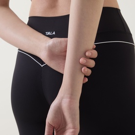 Model wearing Tala Shadow Black leggings with white contrast trim detail, close-up back view showing waistband and seam detailing