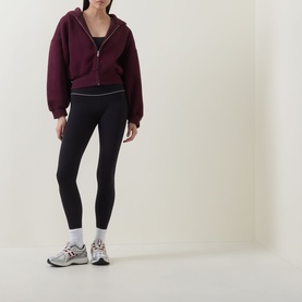 Model wearing Tala Shadow Black leggings with a burgundy zip-up hoodie and grey trainers.