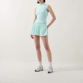 Model wearing Tala SkinLuxe Ruched Floaty Shorts in Soft Mint with matching sleeveless top, white socks and grey trainers.