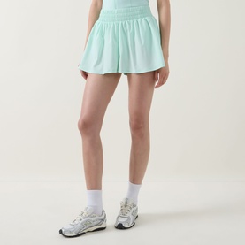 Model wearing Tala SkinLuxe Ruched Floaty Shorts in Soft Mint with white ankle socks and grey chunky trainers.