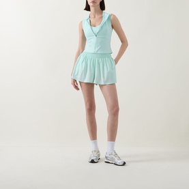 Model wearing Tala SkinLuxe Ruched Floaty Shorts in Soft Mint with matching vest top, white socks and silver trainers.
