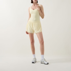 Model wearing Tala SkinLuxe Contrast Piping Tank Top in Lemon Yellow with matching shorts and white trainers.