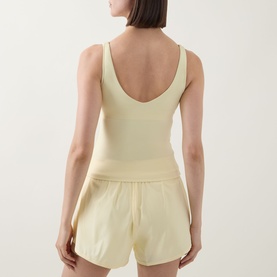 Model wearing Tala SkinLuxe Contrast Piping Tank Top in Lemon Yellow, showing deep scoop back detail, styled with matching yellow shorts.