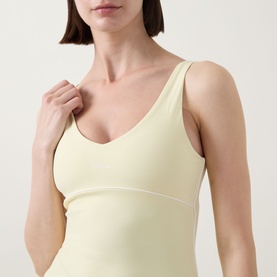 Model wearing Tala SkinLuxe Contrast Piping Tank Top in Lemon Yellow, featuring V-neckline and contrast piping detail.