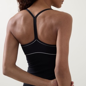 Model wearing Tala top in Shadow Black, shown from back, with Y-strap racerback detail and contrast white seam trim.