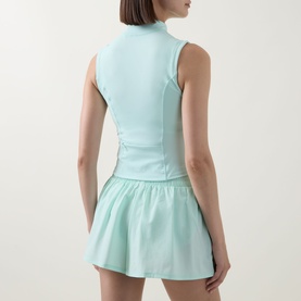 Model wearing Tala SkinLuxe Zip Through Running Top in Soft Mint, sleeveless with mock neck, styled with matching mint flared skirt.