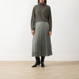 Model wearing Vince light green pleated midi skirt, styled with matching knit turtleneck and black heeled ankle boots