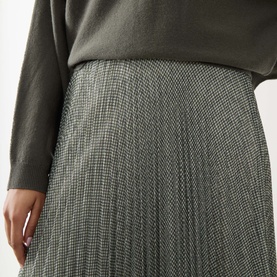 Model wearing Vince light green houndstooth pleated midi skirt, styled with a dark grey knit top.