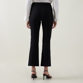 Model wearing Vince black cropped flare trousers, rear view, styled with white top and black heeled mules