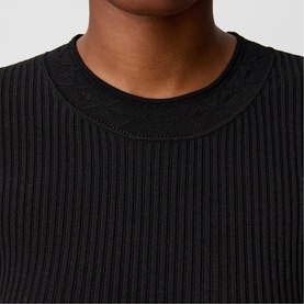 Model wearing Claude Pierlot black ribbed knit top with crew neckline, close-up detail shot.