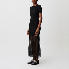 Model wearing Claude Pierlot black short-sleeve midi dress with sheer pleated fringe hem, styled with black lace-up flatform shoes.