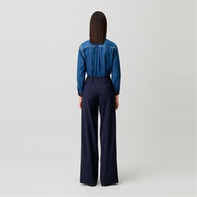 Model wearing Claude Pierlot Straight Leg Trousers in blue, wide-leg silhouette with thick waistband, styled with a blue denim top.