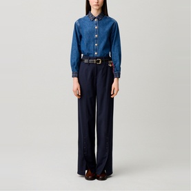 Model wearing Claude Pierlot Straight Leg Trousers in blue with wide-leg silhouette and thick waistband, styled with denim shirt and brown belt.