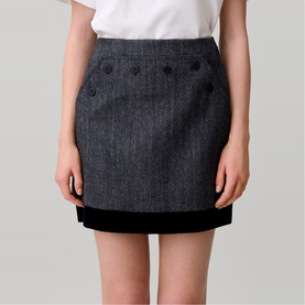 Model wearing Claude Pierlot black mini skirt with decorative button detail and velvet hem trim, styled with a white top.