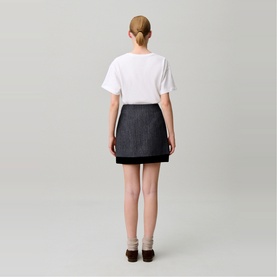 Model wearing Claude Pierlot black mini skirt, rear view, styled with white T-shirt and brown loafers