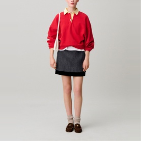 Model wearing Claude Pierlot black mini skirt with red rugby polo shirt, white underlayer, cream socks and brown loafers