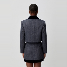 Model wearing Claude Pierlot black woven blazer with velvet collar, styled with matching mini skirt, rear view.