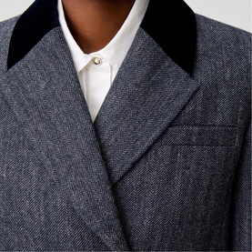 Model wearing Claude Pierlot black herringbone blazer with velvet collar, styled with white shirt and pearl pin brooch