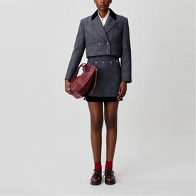 Model wearing Claude Pierlot black mini skirt and matching cropped blazer, styled with a burgundy bag and red loafers