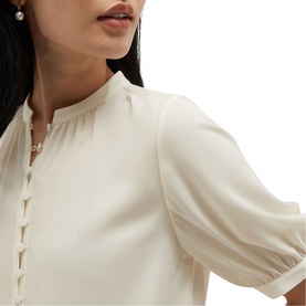 Model wearing Hobbs cream dress with mandarin collar, pearl button fastening, and puff sleeves