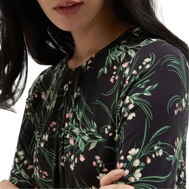 Model wearing Hobbs navy multi floral print top with tie neck detail and short sleeves, featuring green leaf and pink blossom pattern