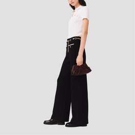 Model wearing Maje Womens French Dress in red, styled with black wide-leg trousers, black flats, and carrying a small burgundy clutch bag.
