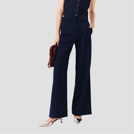 Model wearing Maje wide-leg navy trousers with front pleats, styled with a matching navy top, silver kitten heels, and burgundy clutch bag.