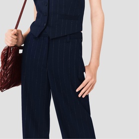 Model wearing Maje navy pinstripe wide-leg trousers and matching waistcoat, styled with a burgundy shoulder bag.