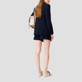 Model wearing Maje Womens French Dress in navy, styled with matching shorts, carrying a beige backpack and wearing cream trainers.