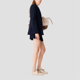 Model wearing Maje Womens French Dress in navy, styled with a beige bucket bag and cream trainers with ankle socks.