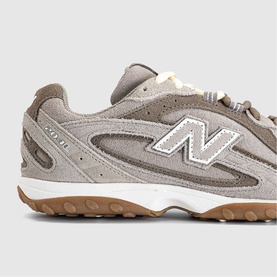 New Balance trainer in Dark Olivine Gum, grey suede upper with white N logo and gum rubber sole, close-up detail shot