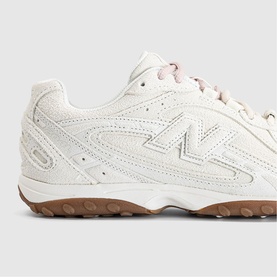 New Balance trainer in Sea Salt Gum colourway, off-white perforated upper with tonal logo detail and gum rubber outsole.