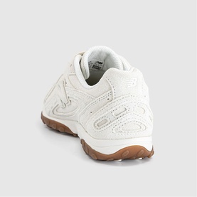 New Balance trainer in Sea Salt Gum, white leather upper with tonal embossed detailing and tan gum rubber sole, rear view.
