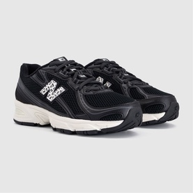 New Balance 830 trainers in black with leopard-print logo panels, white chunky sole and silver N branding, three-quarter view