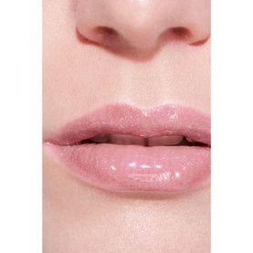 Model with Chanel lip gloss in shade 432 Cristal, a sheer glossy pink, shown close up on lips