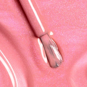 Chanel nail varnish in 421 Cristalline, sheer pink shimmer formula shown with applicator brush on glittery pink surface