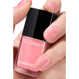 Chanel Le Vernis nail varnish in 421 Cristalline, sheer pink shade, shown on manicured hand with bottle in foreground