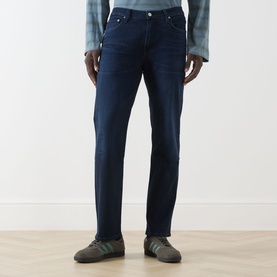 Model wearing Citizens of Humanity 3049 straight jeans in blue, styled with a check shirt and grey trainers.