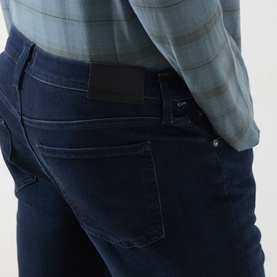 Model wearing Citizens of Humanity 3049 Straight Jeans in blue, rear view showing back pockets and patch label, styled with plaid shirt.