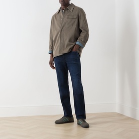Model wearing Citizens of Humanity 3049 straight jeans in blue, styled with a taupe overshirt and grey trainers.